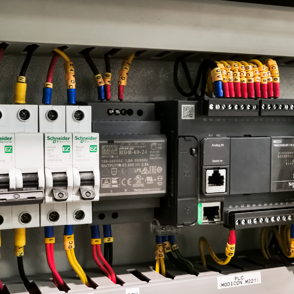 PLC och elskåp i industriell automation med kopplade kablar och styrmoduler i produktionsmiljö.